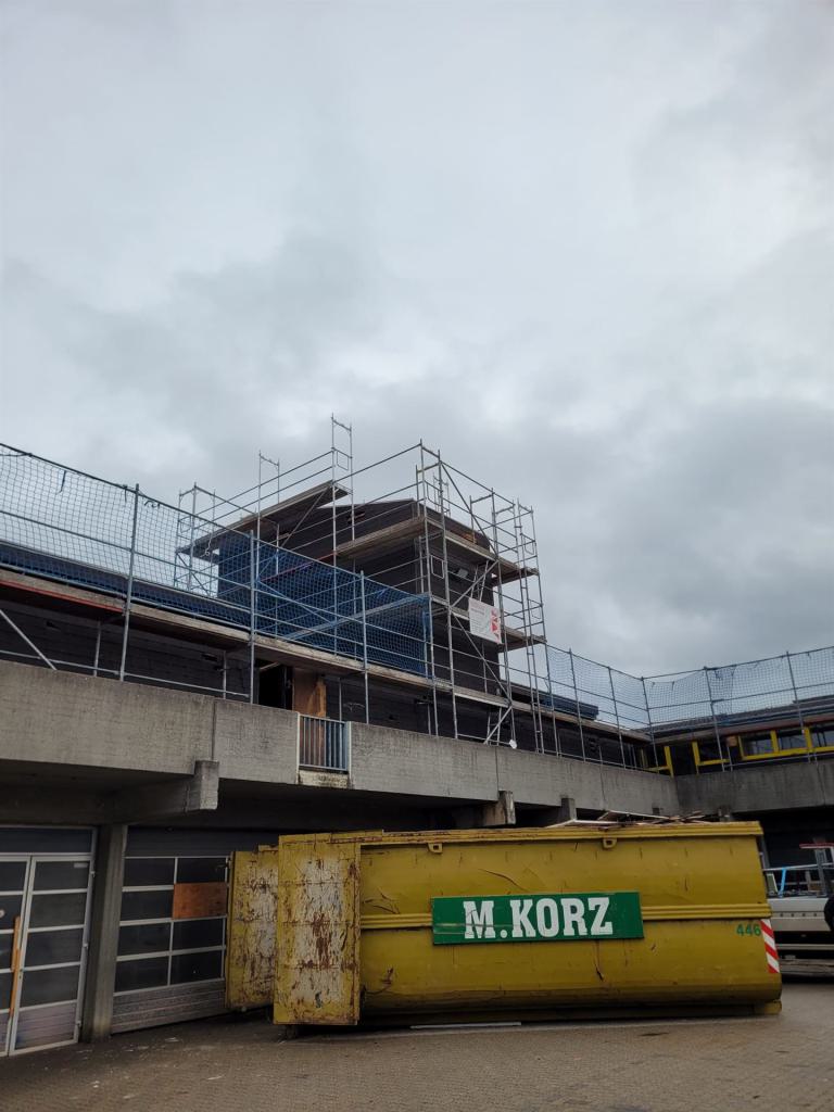 Baugerüst auf einem Flachbau mit eingerüstetem Turm